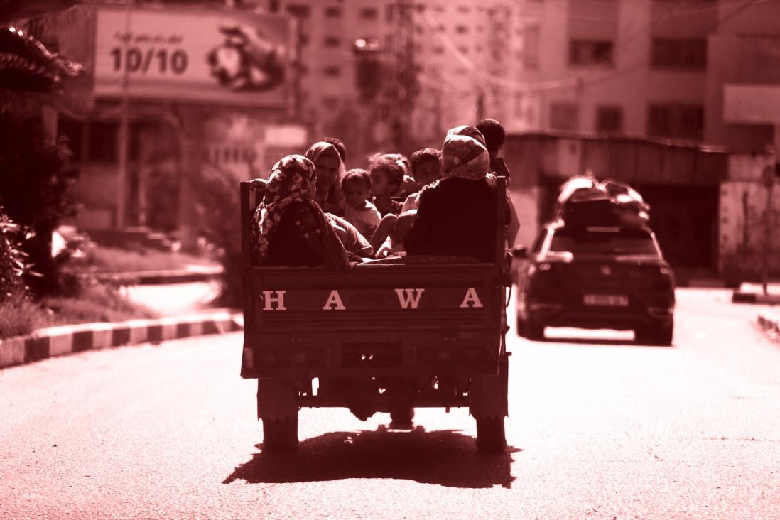 Two young Palestinians carry an eledey men on a wheel chair in Gaza